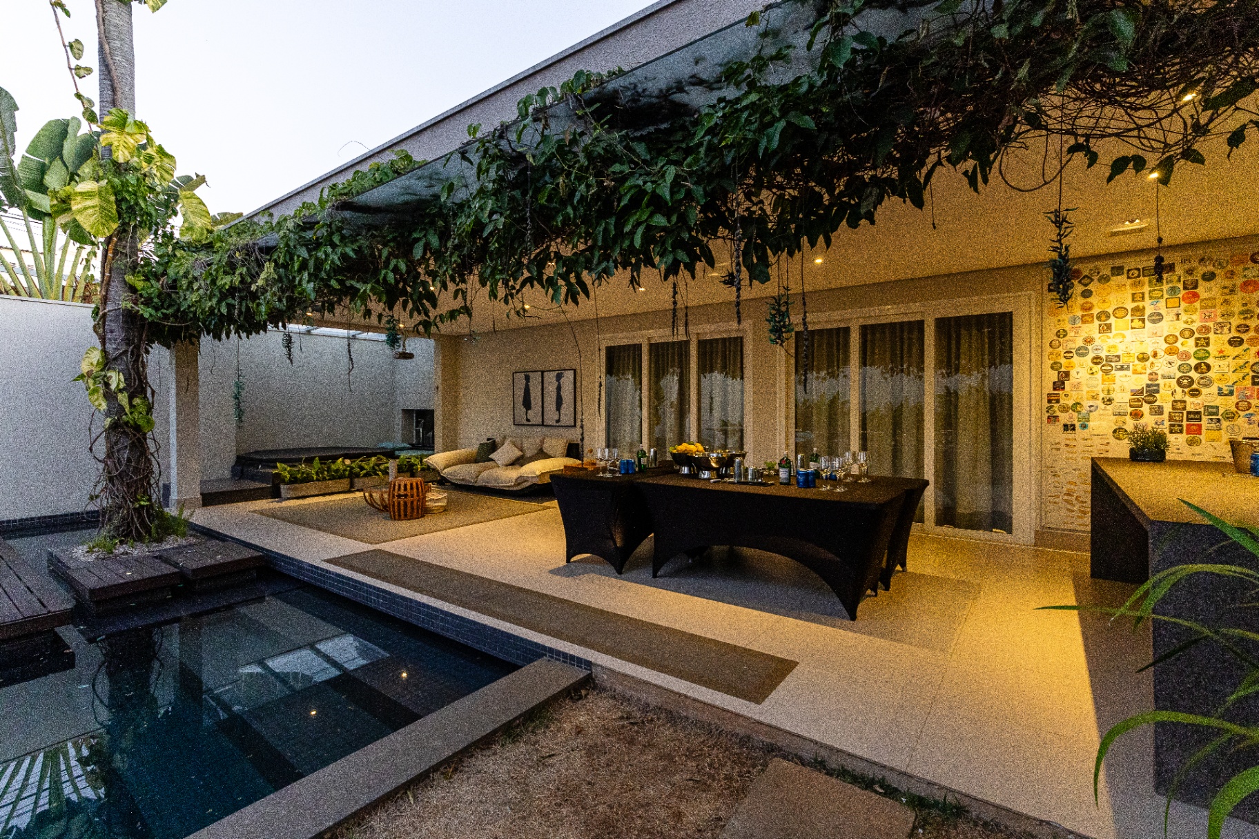 Área externa com piscina, pergolado e mesa montada para evento